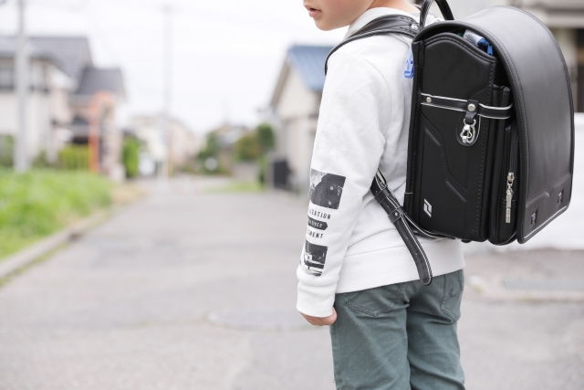 ランドセルを背負った男の子が振り返っている写真