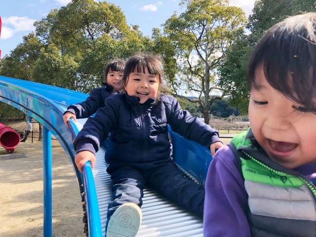 3人の子どもが滑り台を滑っている写真